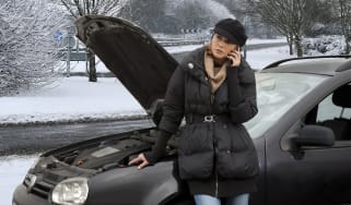 Woman on phone next to broken-down car