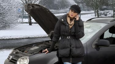 Woman on phone next to broken-down car