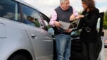 Two people talking over a car brochure