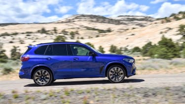 BMW X5 M Competition driving on gravel - side view