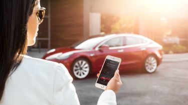 Woman looking at phone in front of a Tesla