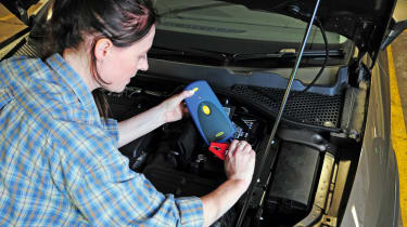 Woman checking the charge of a car battery