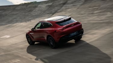 Aston Martin DBX driving on banked circuit - rear view