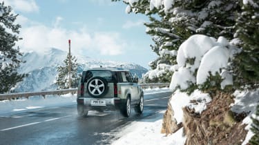 Land Rover Defender driving on road - rear view